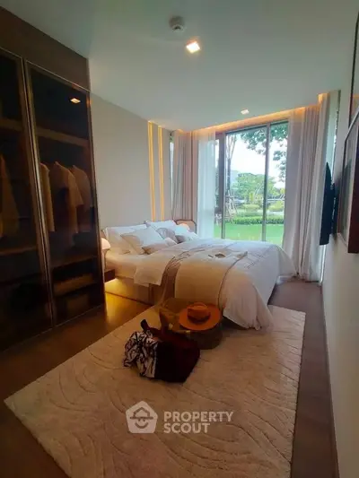 Luxurious bedroom with large window and elegant decor, offering a serene garden view.