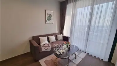 Stylish living room with modern sofa and elegant decor, featuring large windows and natural light.