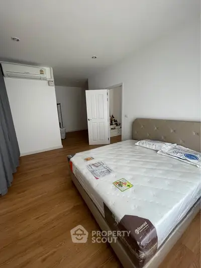 Spacious bedroom with modern design and natural light, featuring a comfortable bed and sleek wooden flooring.
