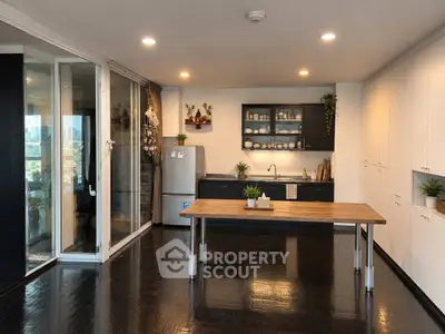 Spacious modern kitchen with sleek black flooring and open layout, featuring stainless steel appliances and ample storage.