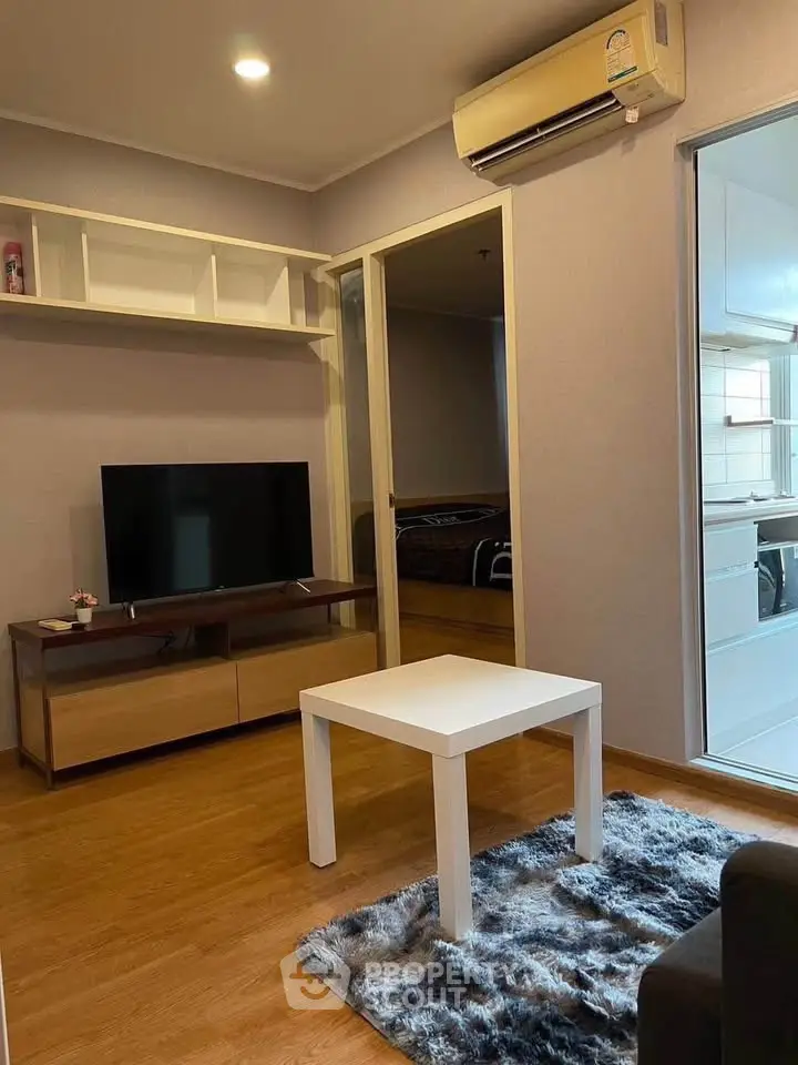 Cozy living room with modern decor, featuring a TV and air conditioning, perfect for relaxation.