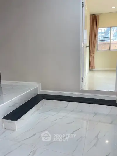Modern interior with marble flooring and open doorway leading to sunlit room