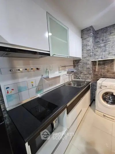 Modern kitchen with sleek cabinets, electric stove, and washing machine in compact layout.