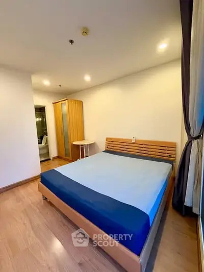 Spacious bedroom with wooden flooring and modern furnishings in a cozy apartment.