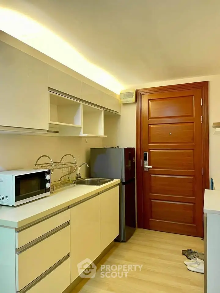 Modern kitchen with sleek cabinetry, microwave, and compact fridge in a cozy apartment setting.