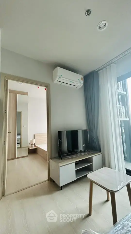 Modern living room with TV and air conditioning, adjacent to a cozy bedroom.