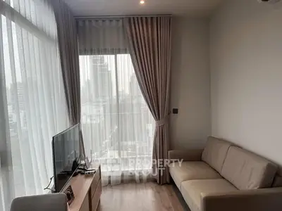 Modern living room with city view, featuring cozy sofa and TV setup.