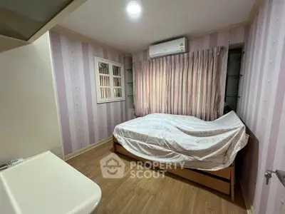 Cozy bedroom with wooden flooring and air conditioning in modern apartment