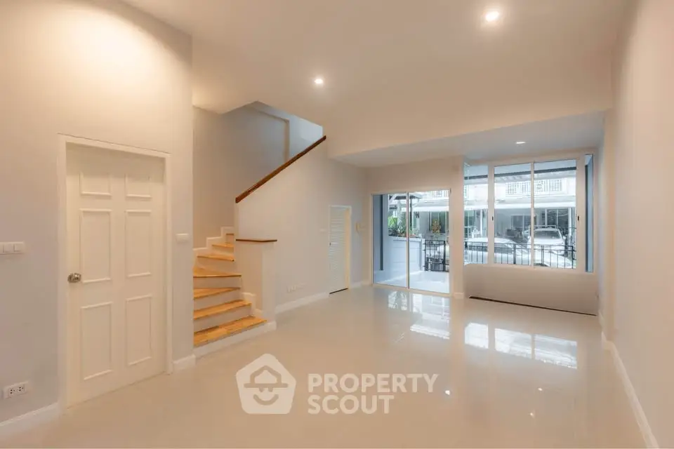 Spacious modern living room with staircase and large windows offering natural light.
