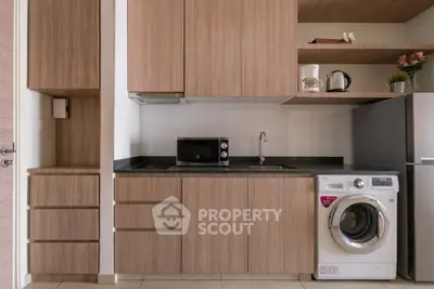 Modern kitchen with wooden cabinetry, washing machine, and microwave in compact layout.
