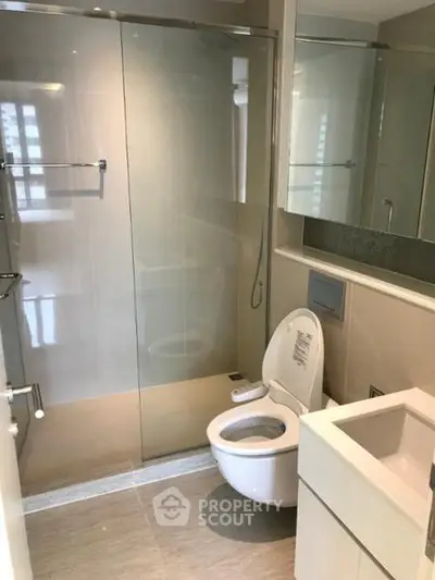 Modern bathroom with sleek design and glass shower enclosure in a contemporary apartment.