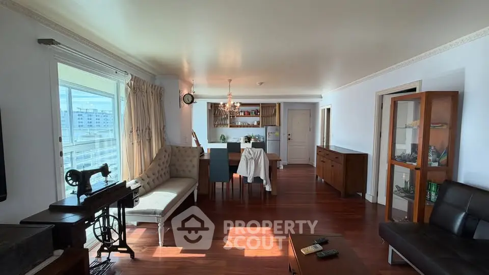 Spacious living room with elegant dining area and large windows offering city views.