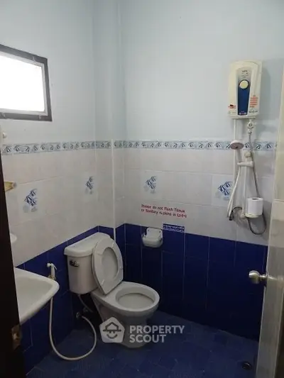 Compact bathroom with blue tiles and wall-mounted water heater