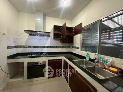 Modern kitchen with sleek black countertops and built-in gas stove and oven.