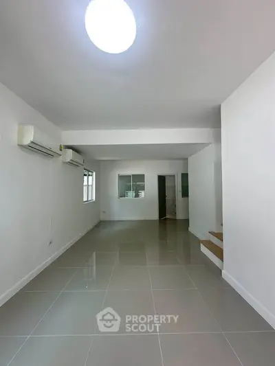 Spacious modern living room with sleek tile flooring and air conditioning, perfect for comfortable living.