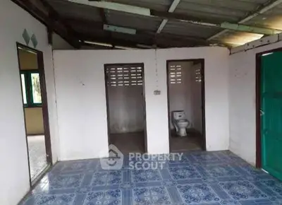 Rustic interior with tiled floor and visible bathroom area, potential for renovation.