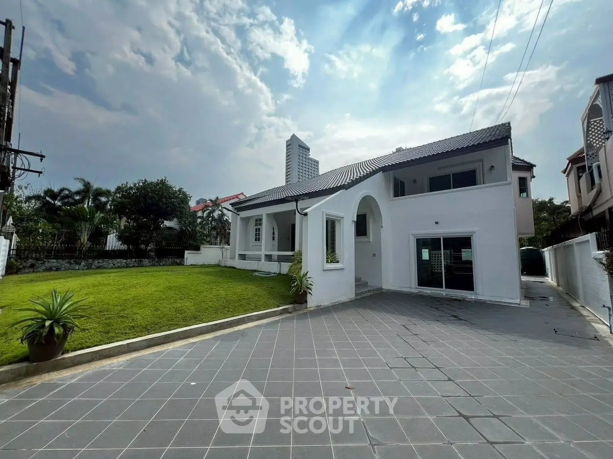 Stunning modern white house with spacious driveway and lush green lawn in a serene neighborhood.