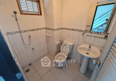 Modern bathroom with shower, toilet, and sink in a tiled setting.