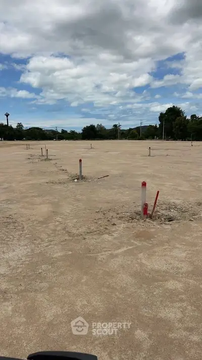 Vacant land plot ready for development under a partly cloudy sky.