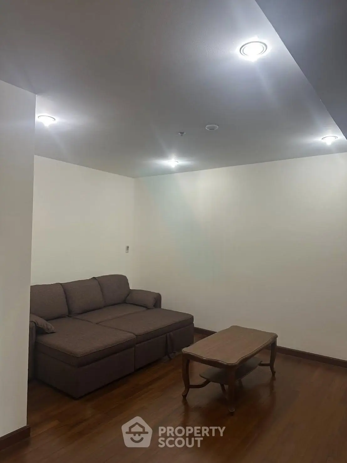 Cozy living room with elegant wooden flooring and comfortable sofa, perfect for relaxation.