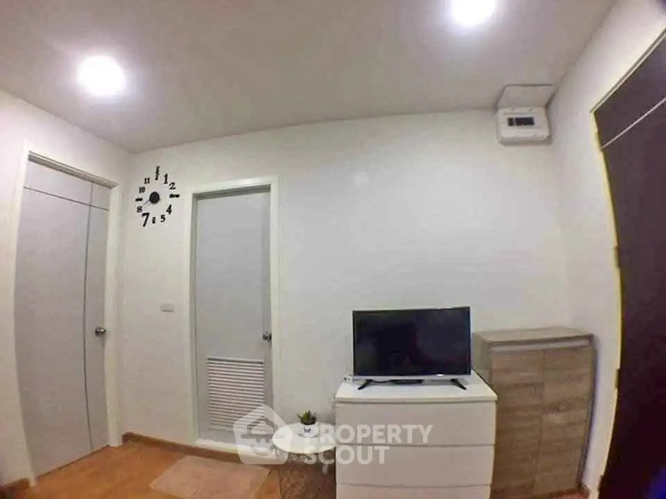 Cozy modern living room with wall clock and TV on a white dresser, perfect for relaxation.