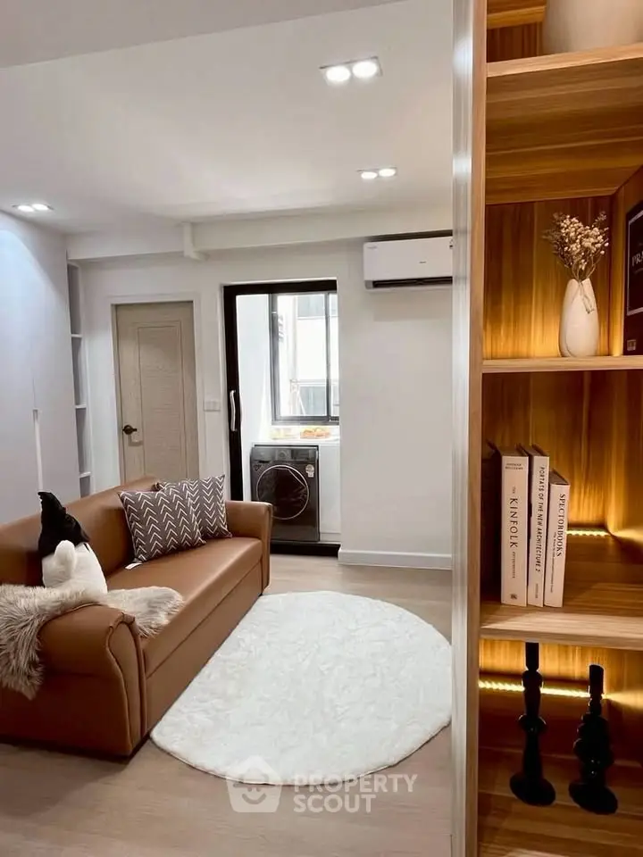 Modern living room with cozy sofa, stylish bookshelf, and washer in bright apartment.