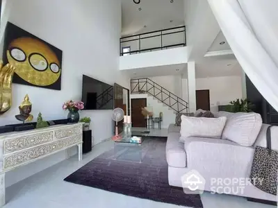 Elegant living room with high ceiling, modern decor, and a cozy sofa set, complemented by an artistic staircase leading to an upper level.