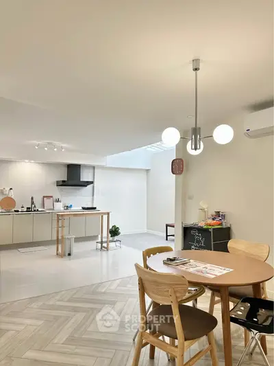 Modern open-plan kitchen and dining area with stylish lighting and wooden flooring.