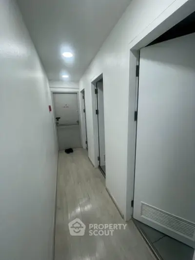 Modern hallway with white walls and wooden flooring in a residential building.