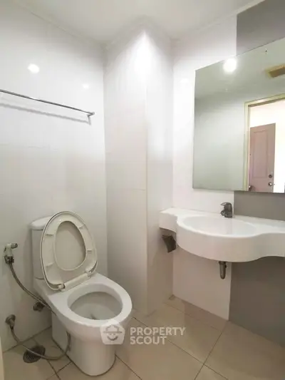 Modern bathroom with sleek fixtures and minimalist design, featuring a wall-mounted sink and toilet.