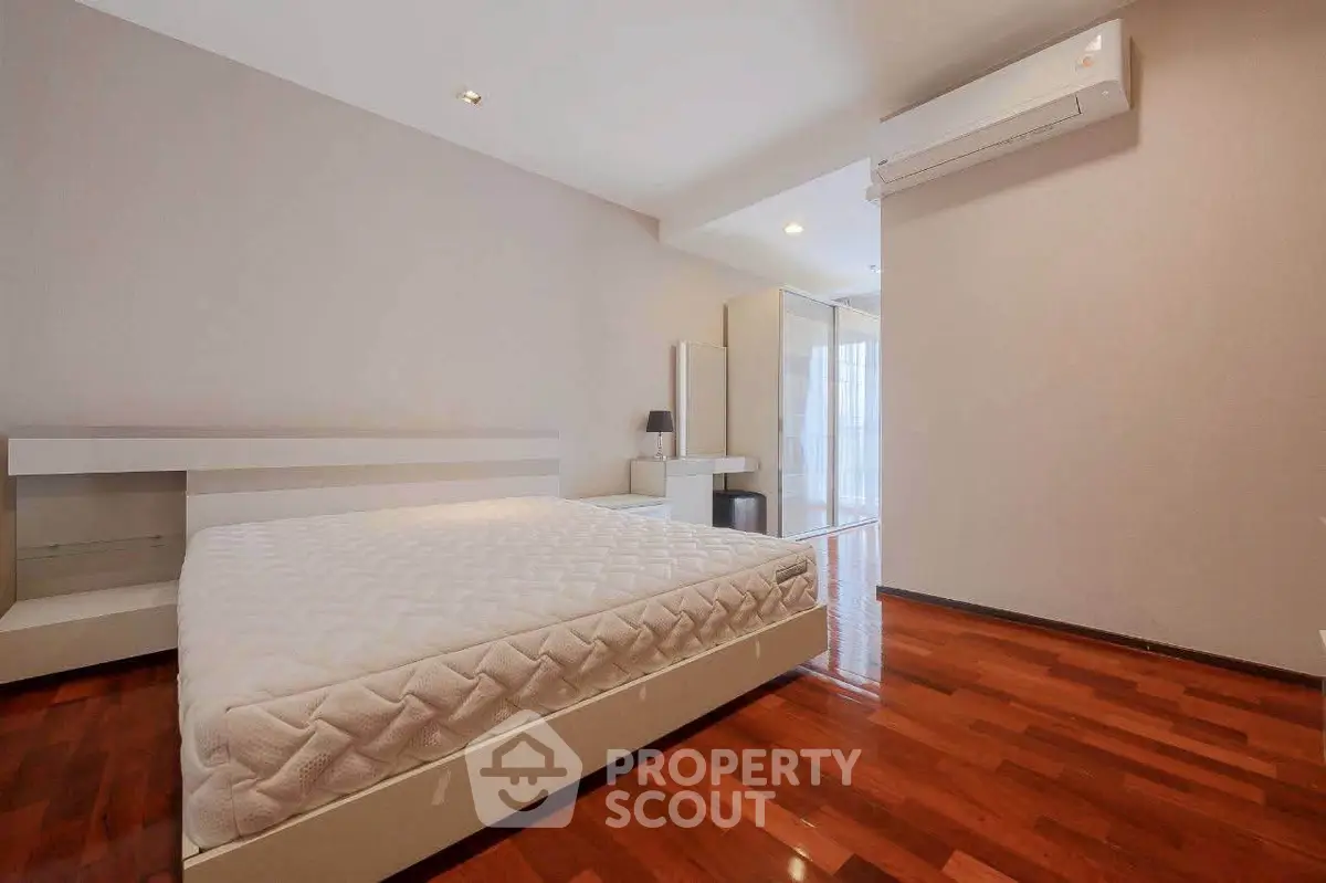 Spacious bedroom with hardwood floors and modern air conditioning unit.