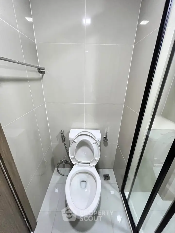 Modern bathroom with sleek design and glass shower door in contemporary apartment.