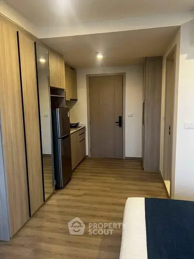 Modern studio apartment with sleek wooden flooring and compact kitchen area.