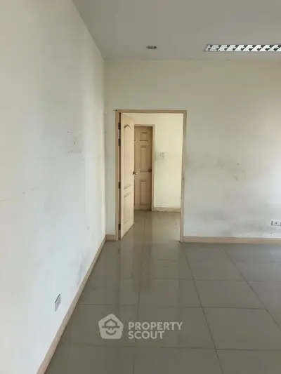 Spacious empty room with tiled flooring and neutral walls, ideal for customization.