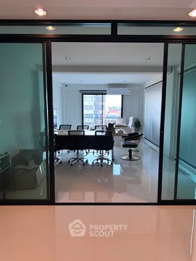 Modern office space with glass doors and city view, ideal for professional meetings.