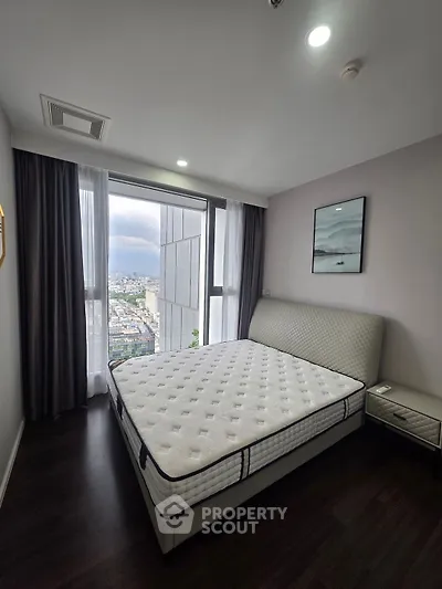Modern bedroom with city view, featuring a large window and stylish decor.