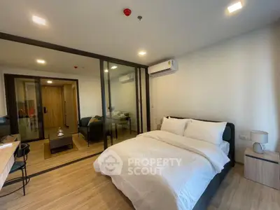 Modern bedroom with glass partition and cozy living area in a stylish apartment.