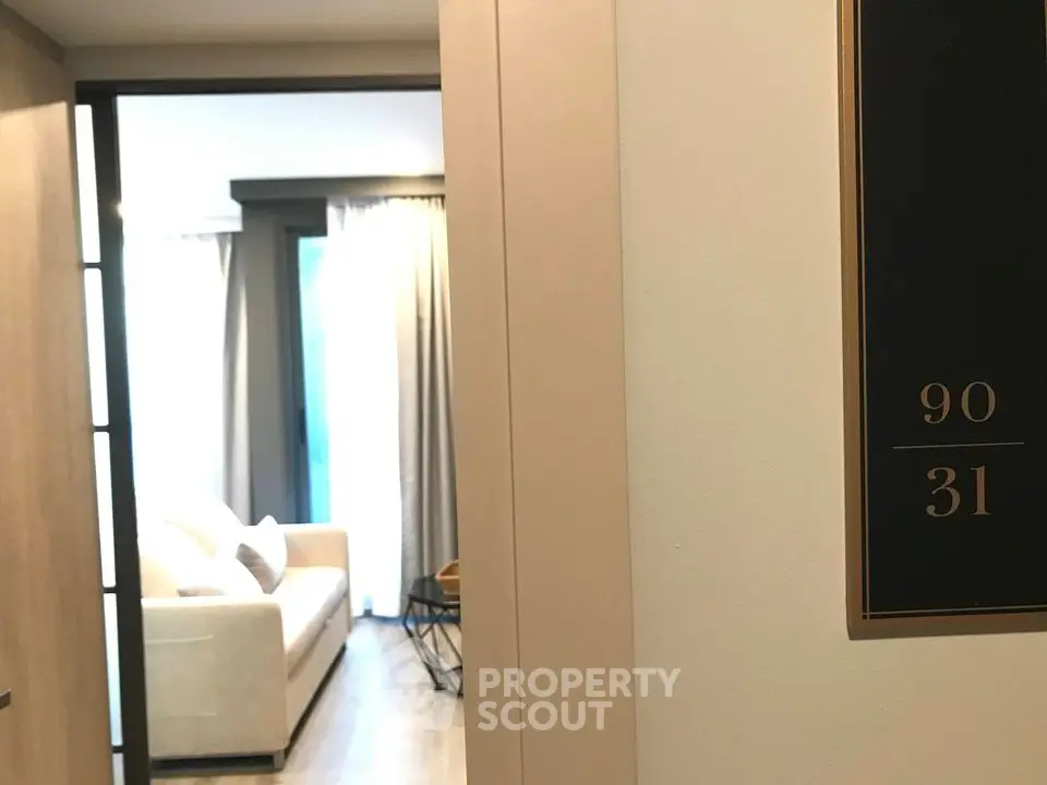 Modern apartment entrance with a glimpse of a cozy living room featuring a comfortable sofa and stylish decor.