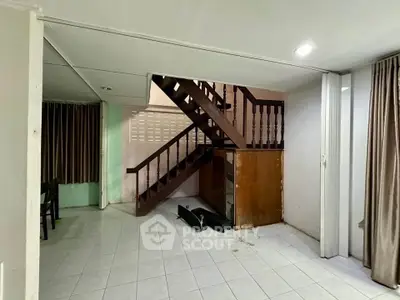 Spacious interior with wooden staircase and tiled flooring, ideal for renovation.