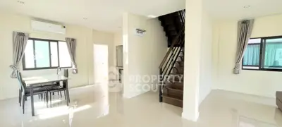 Spacious modern living room with dining area and staircase in bright natural light.