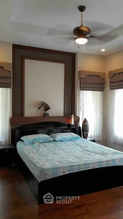 Elegant bedroom with modern decor and ceiling fan, featuring large windows and stylish furnishings.