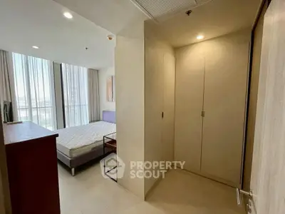 Spacious bedroom with large windows and modern furnishings in a high-rise apartment.