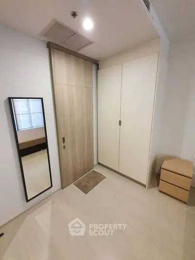 Modern bedroom with sleek wardrobe and full-length mirror, showcasing minimalist design.