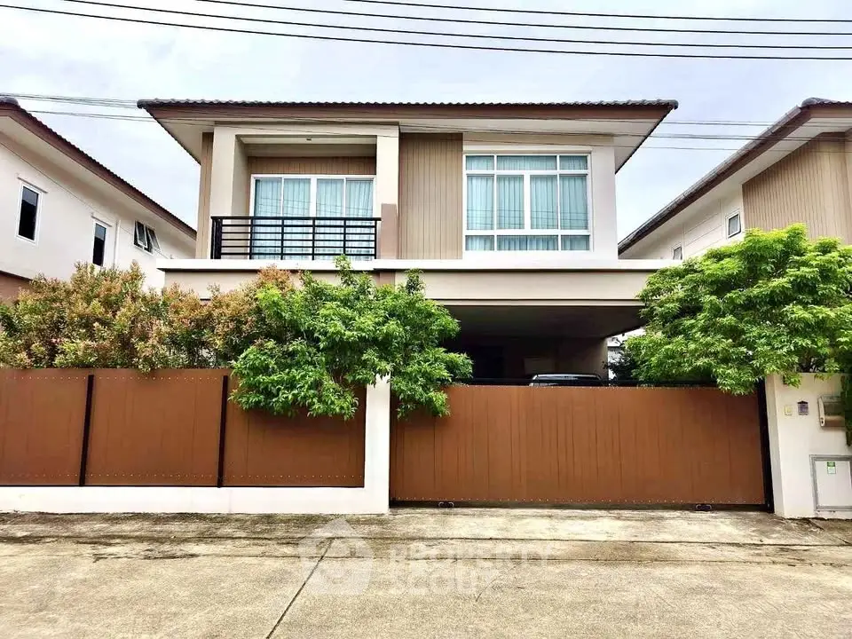 Modern two-story house with a sleek design and lush greenery in a suburban neighborhood.