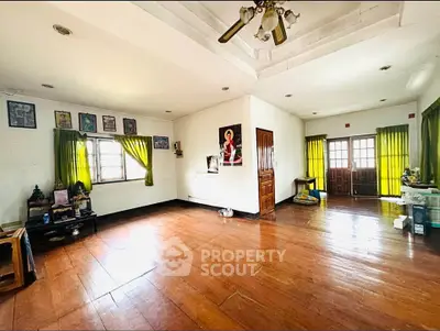 Spacious living room with wooden flooring and natural light, ideal for family gatherings.