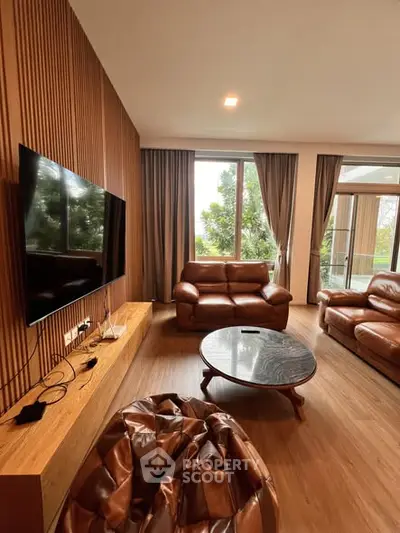 Luxurious living room with leather sofas, large TV, and wooden accents, offering a cozy and elegant ambiance.