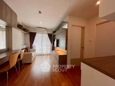 Modern living room with wooden flooring, cozy sofa, and natural light through large windows.