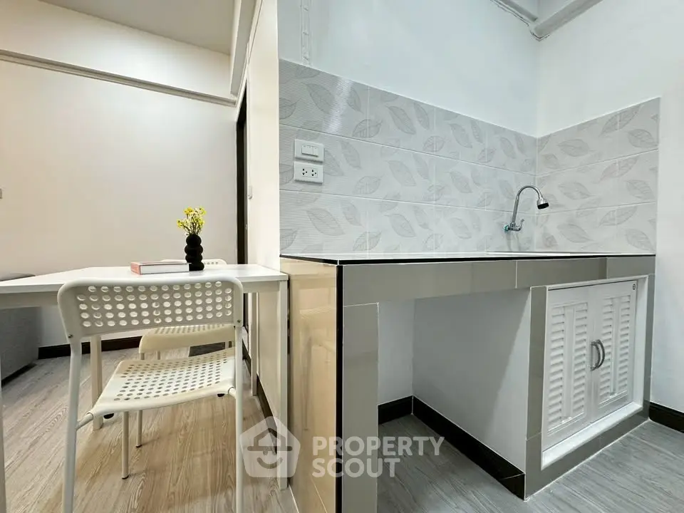 Modern kitchen with sleek design and dining area, featuring stylish backsplash and minimalist furniture.