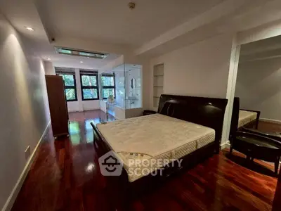 Spacious bedroom with hardwood floors and large windows offering natural light.