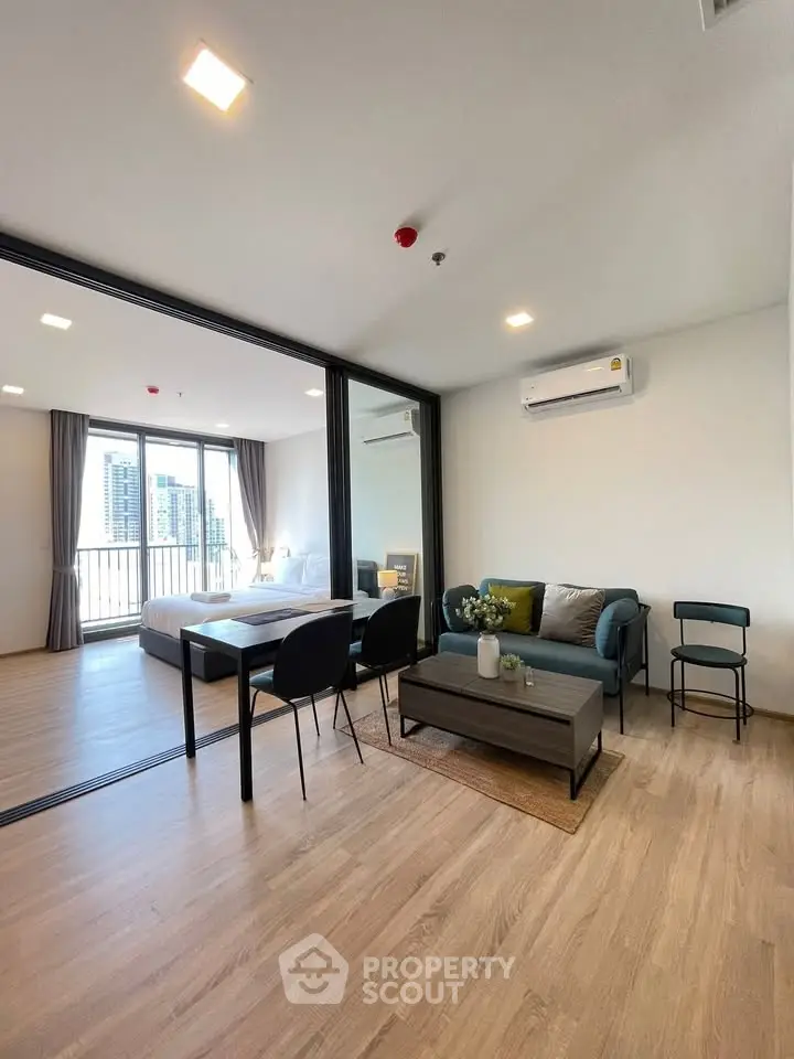 Modern open-plan living room with stylish furniture and city view balcony in a high-rise apartment.